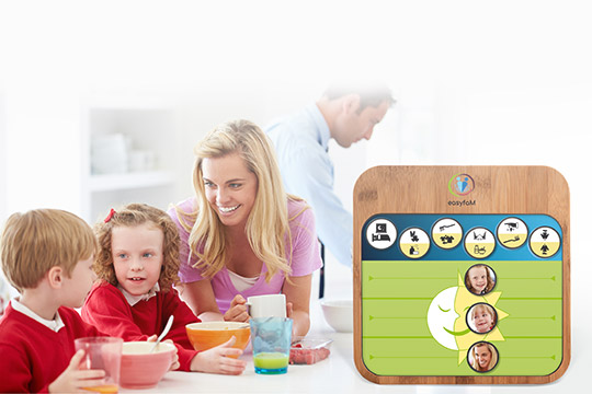 Eine Familie mit zwei Kindern interagiert am Tisch, während ein Lernspielzeug im Vordergrund zu sehen ist.